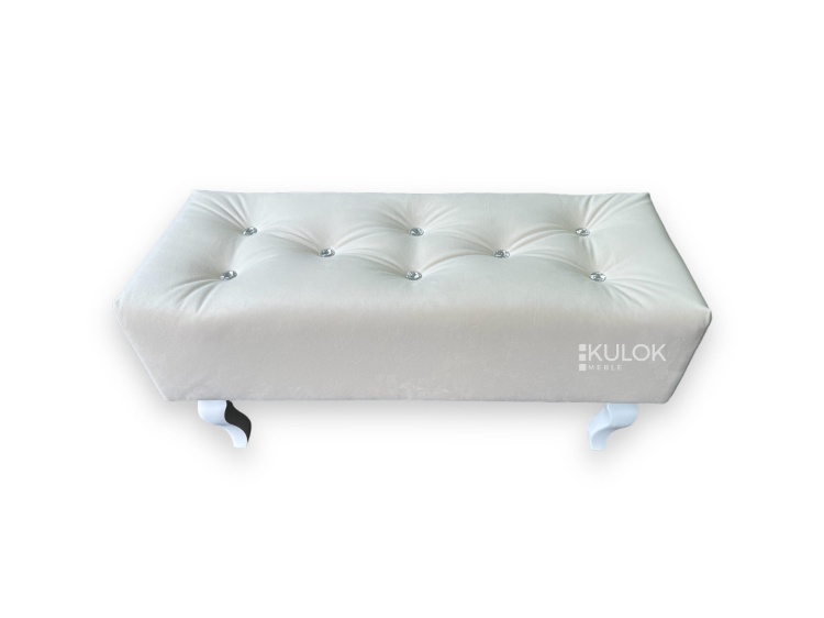 Pufa tapicerowana Chesterfield z białymi nogami.