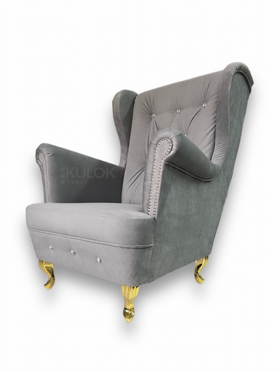 Pikowane oparcie i listwy włoskie - fotel glamour na wysokich nogach