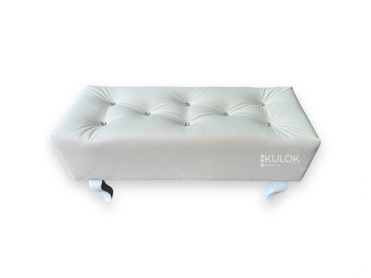 Pufa tapicerowana Chesterfield z białymi nogami.