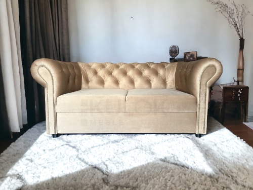 Mała sofka dwuosobowa z funkcją spania w stylu chesterfield w kolorze beżu z guzikami.
