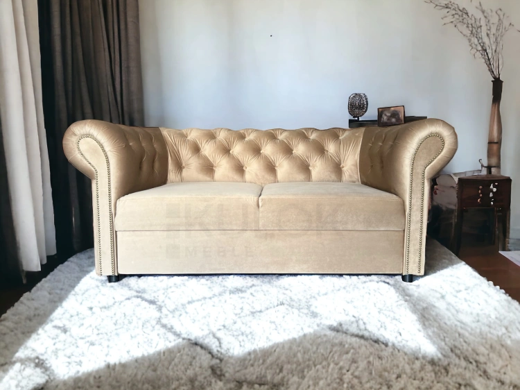 Mała sofka dwuosobowa z funkcją spania w stylu chesterfield w kolorze beżu z guzikami.